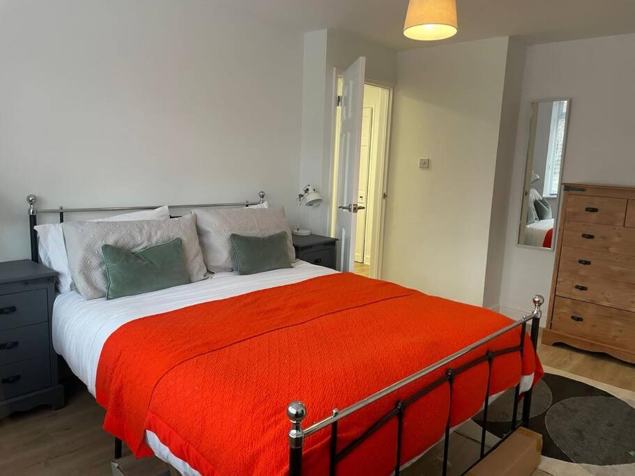 a bedroom with a large bed with a red blanket at Guest Homes - Fairlie Flat in Oxford