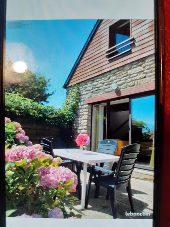une table, des chaises et des fleurs devant un bâtiment dans l'établissement Gite au calme, à Berrien