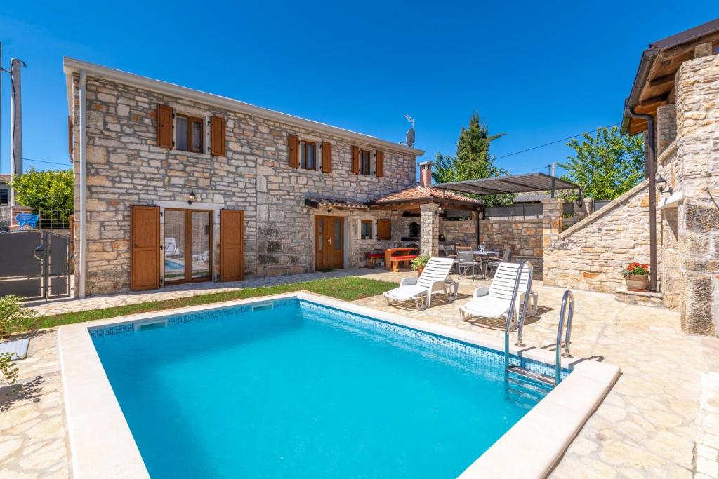 une grande piscine en face d'une maison en pierre dans l'établissement Villa Zinnia, à Fabci