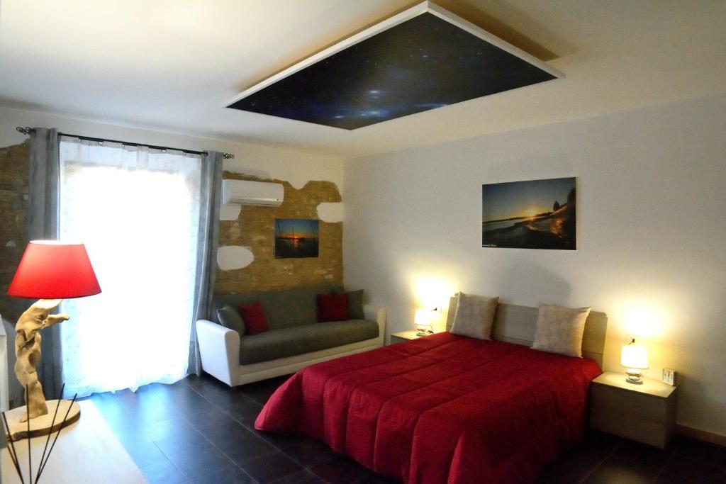 ein Schlafzimmer mit einem roten Bett und einem Sofa in der Unterkunft Casa Kemarin in Campomarino