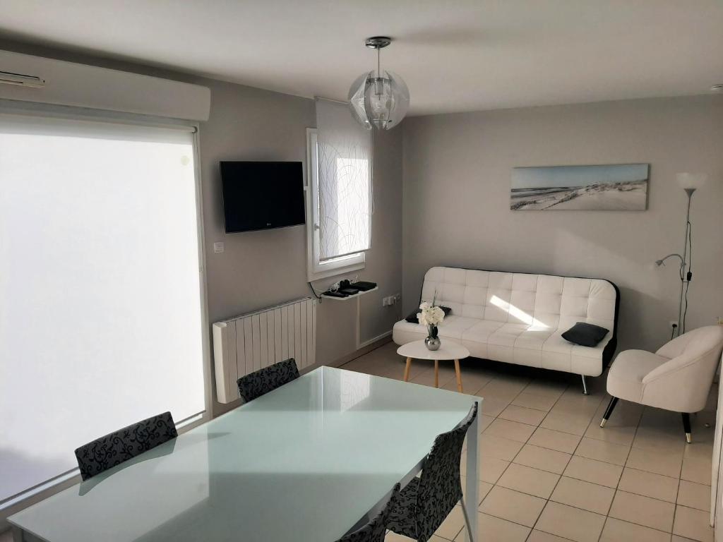 uma sala de estar com uma mesa e um sofá branco em Gîte Cap Goéland - Maison chaleureuse au cœur du site des 2 Caps em Audinghen