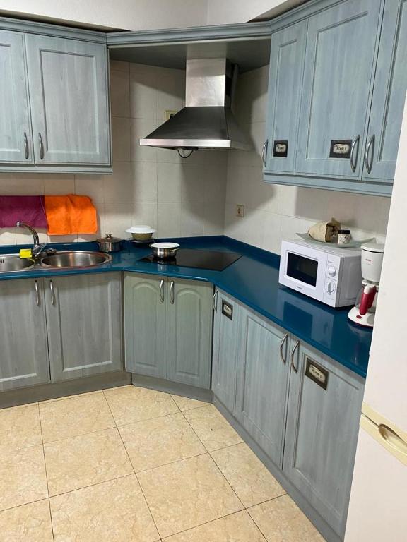 a kitchen with blue cabinets and a microwave at Room Sol Vecindario Gran Canaria Free parking in Vecindario