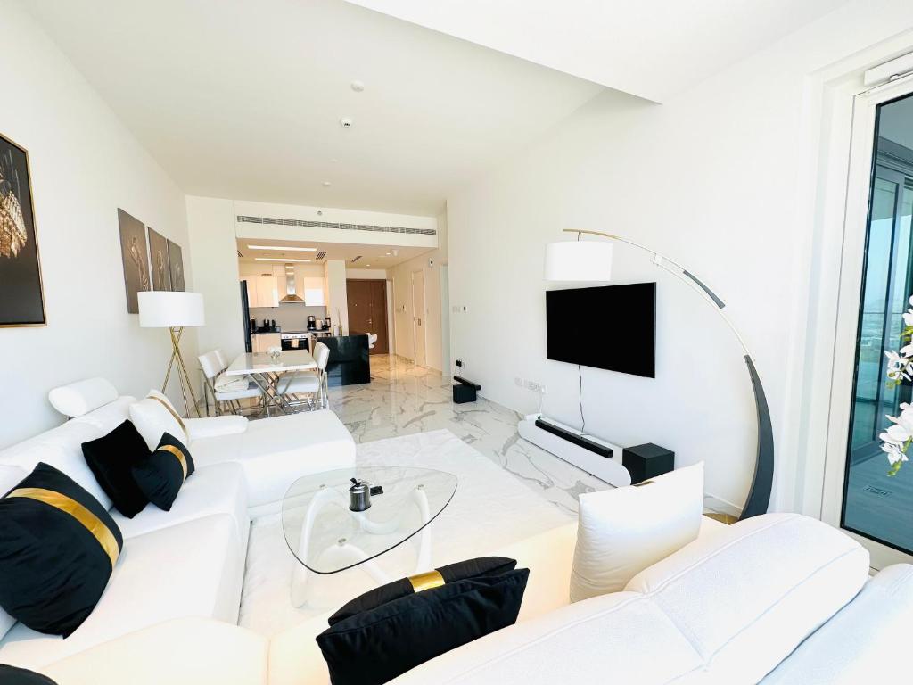 a white living room with a white couch and a tv at Brand New Full Apartment Next to Reem Mall in Abu Dhabi