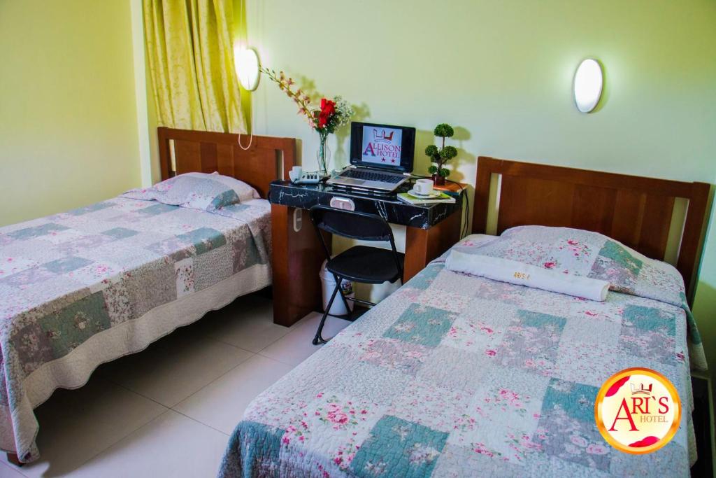 een slaapkamer met 2 bedden en een bureau met een computer bij ALLISON HOTEL in Iquitos