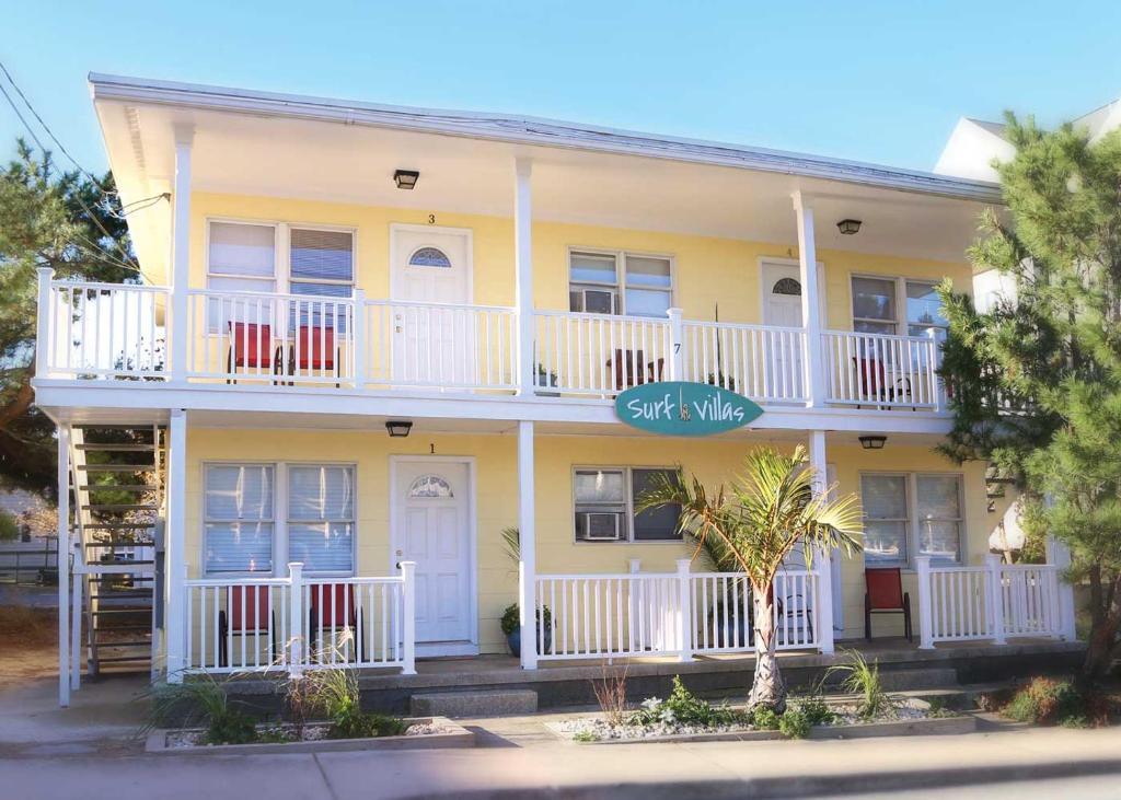 a large yellow house with a white balcony at Surf Villa Apartments in Ocean City