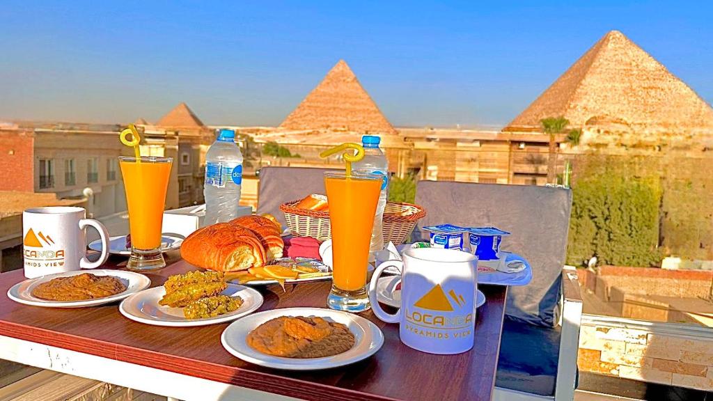 - une table avec des assiettes de nourriture et des boissons sur un balcon dans l'établissement Locanda pyramids view, au Caire