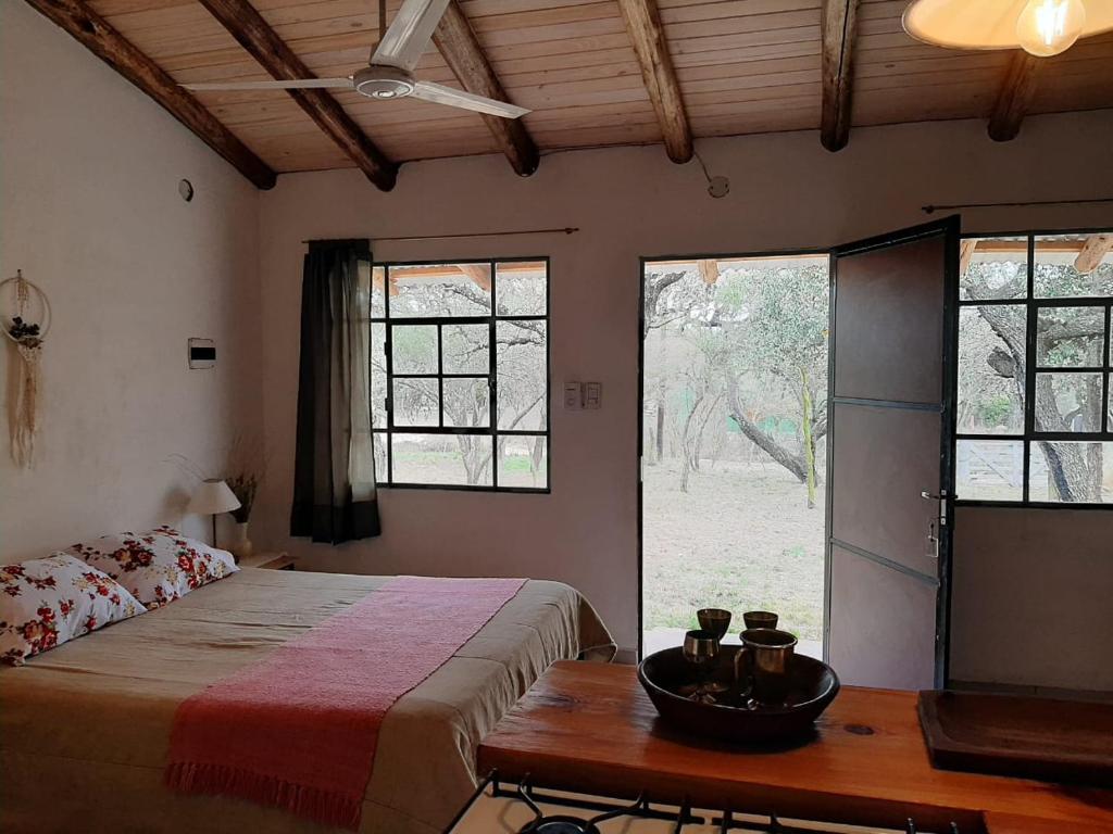 1 dormitorio con cama, mesa y ventanas en PIQUILLIN CASA PARA DOS en Las Rabonas