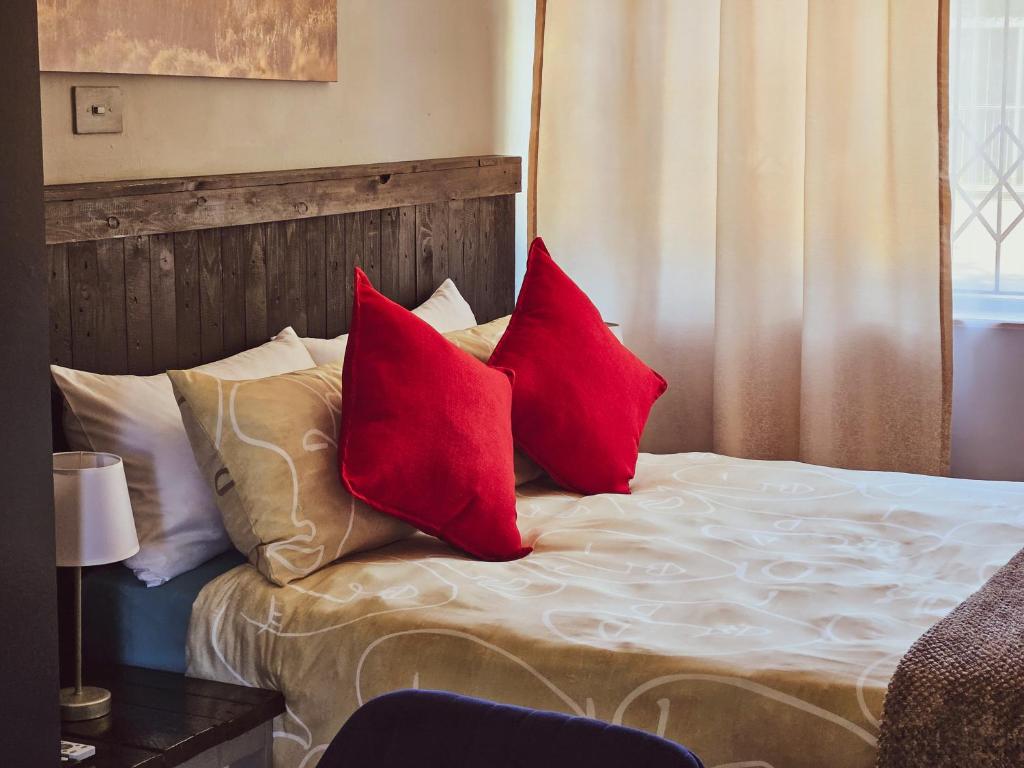 a bed with two red pillows on it at Deluxe Guest Suite at Warner Beach in Kingsborough