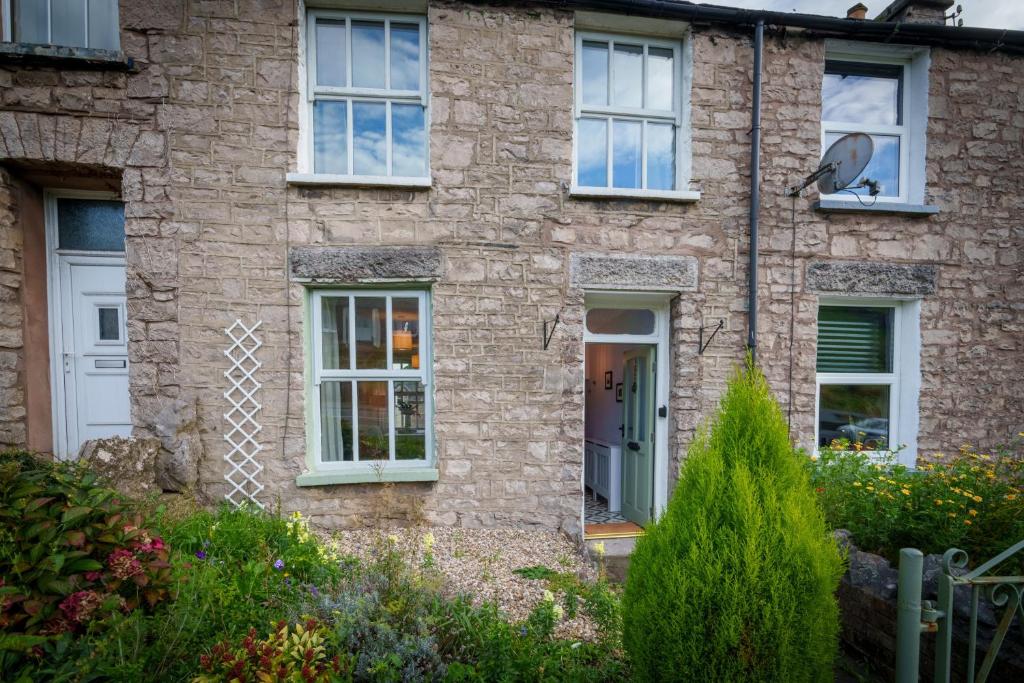 a brick house with a white door and windows at Meadow View - Cosy townhouse with patio garden & parking in Kendal