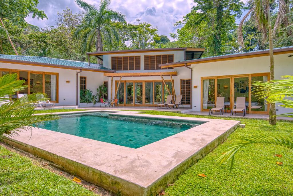 a home with a swimming pool in front of a house at Shawandha Villas in Punta Uva