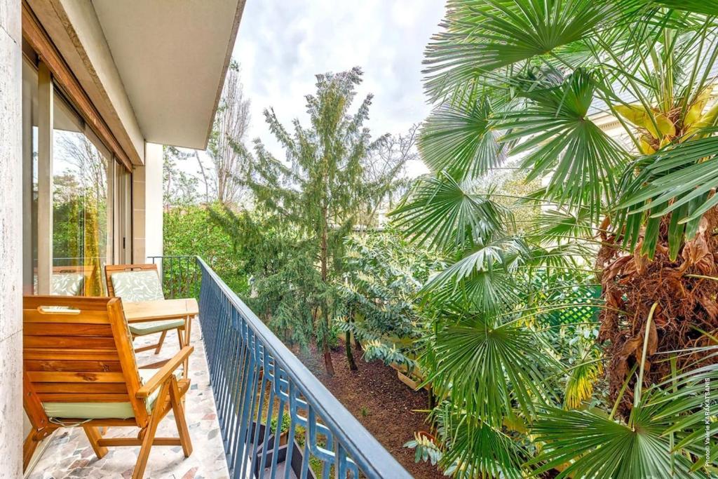 a balcony with a wooden bench and palm trees at Boulogne Billancourt - Schuman 1bdr in Boulogne-Billancourt