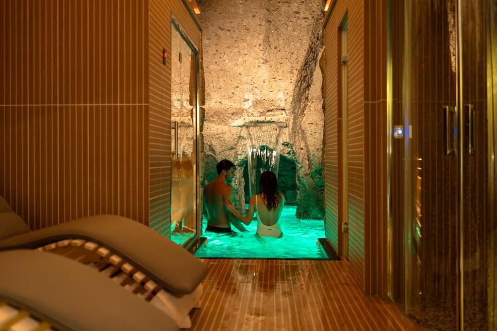 a man and a woman in a swimming pool in a room at Marina Grande Residence & SPA in Sorrento