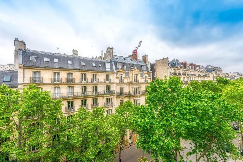 un grand bâtiment avec des arbres devant dans l'établissement Muette - Lamartine 1bdr by B'Your Home, à Paris