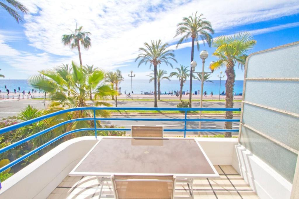 a balcony with a table and chairs and the beach at Promenade des Anglais - Sea View 2bdr in Nice