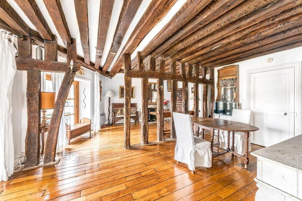 d'une salle à manger avec une table et des plafonds en bois. dans l'établissement Ile Saint Louis - Quai d'Orleans 2bdr, à Paris