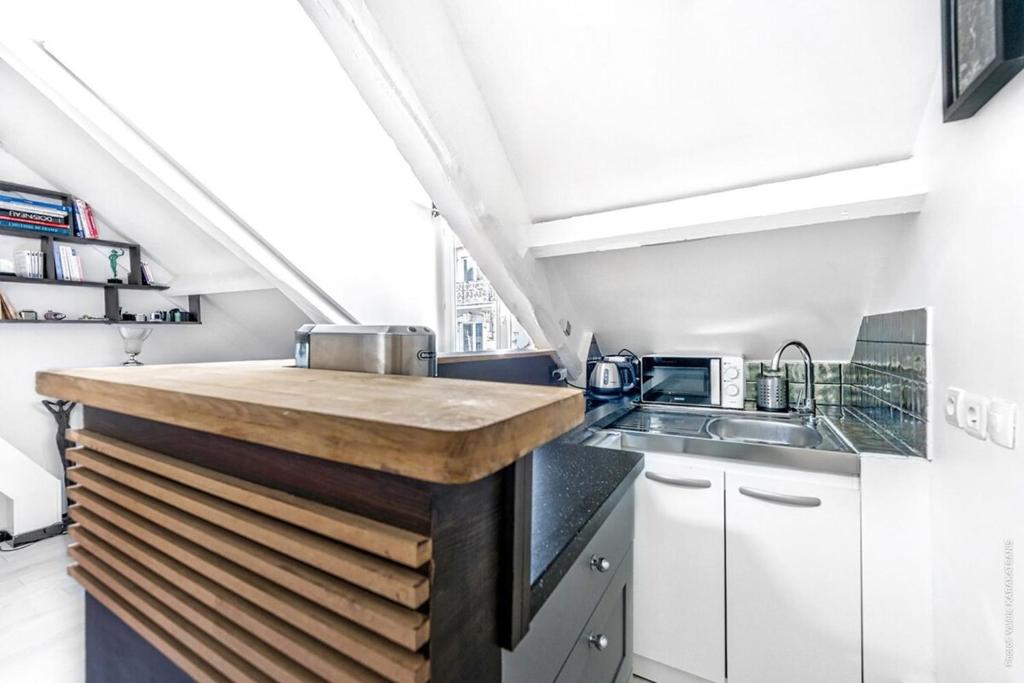 a kitchen with white cabinets and a wooden counter top at Montparnasse - La Gaïté 1bdr in Paris