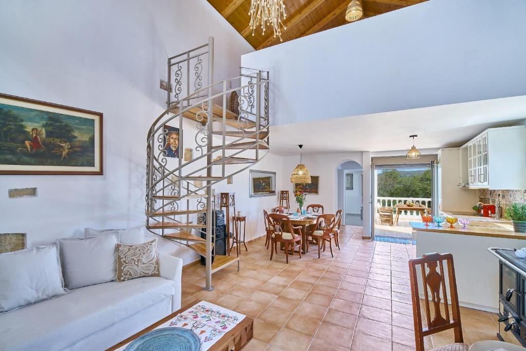 a living room with a spiral staircase and a dining room at La Maison to Chani in Stílos