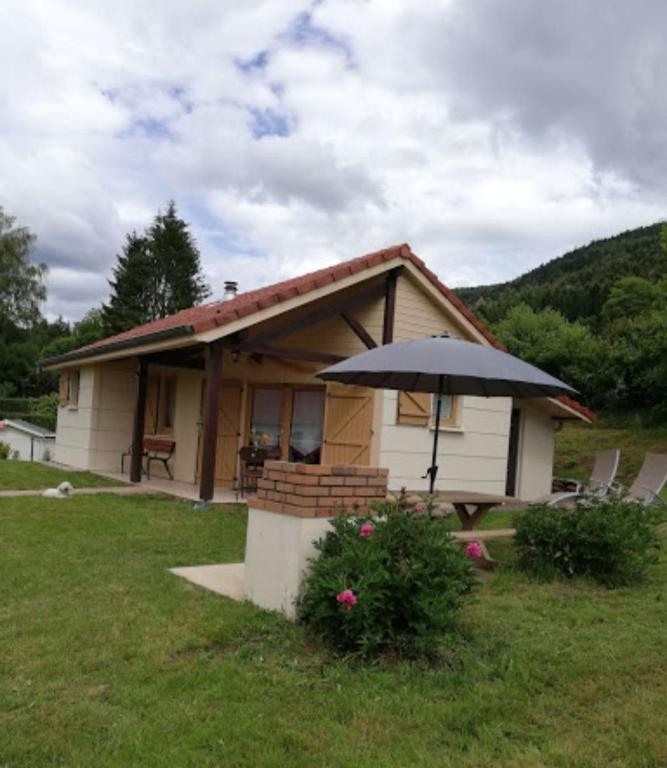 une petite maison avec un parasol dans l'herbe dans l'établissement Chaleureux gîte des brocards aux pieds des sapins 3 étoiles, à Allarmont