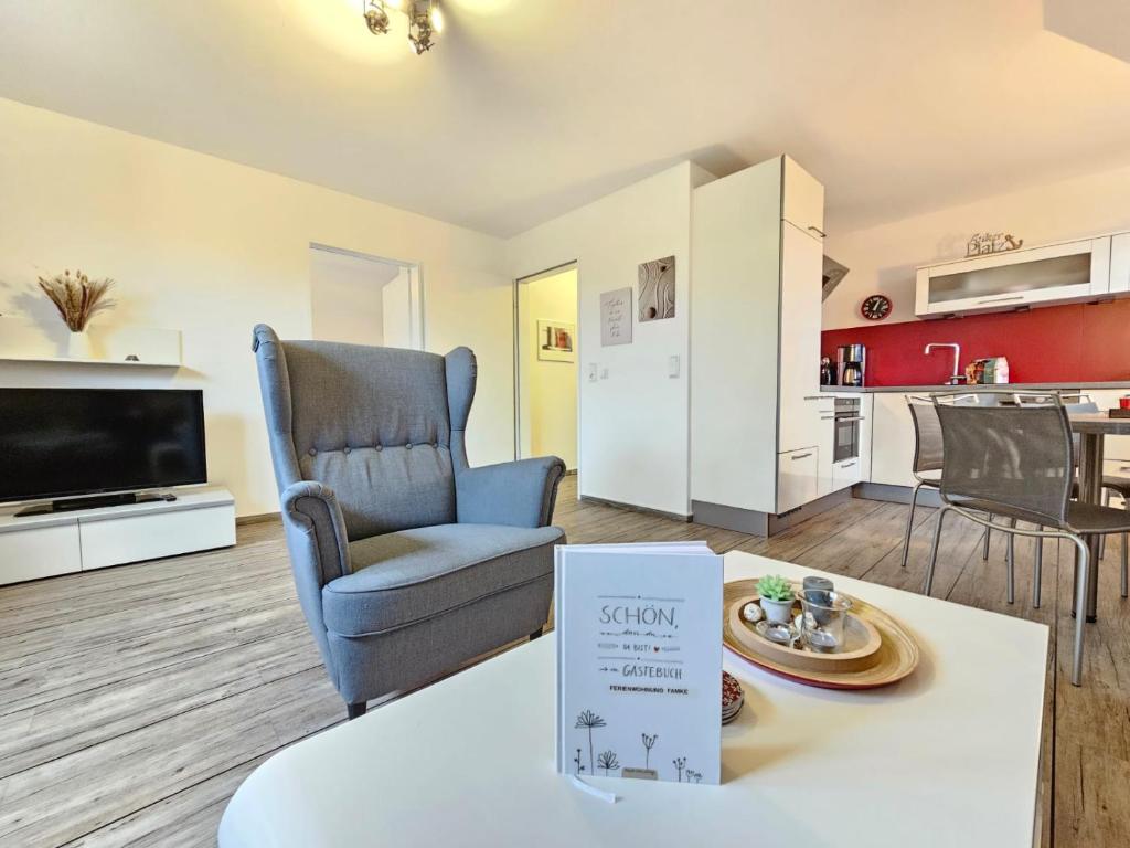 a living room with a chair and a kitchen at Mienhus Apartments Ferienwohnung Famke in Norden