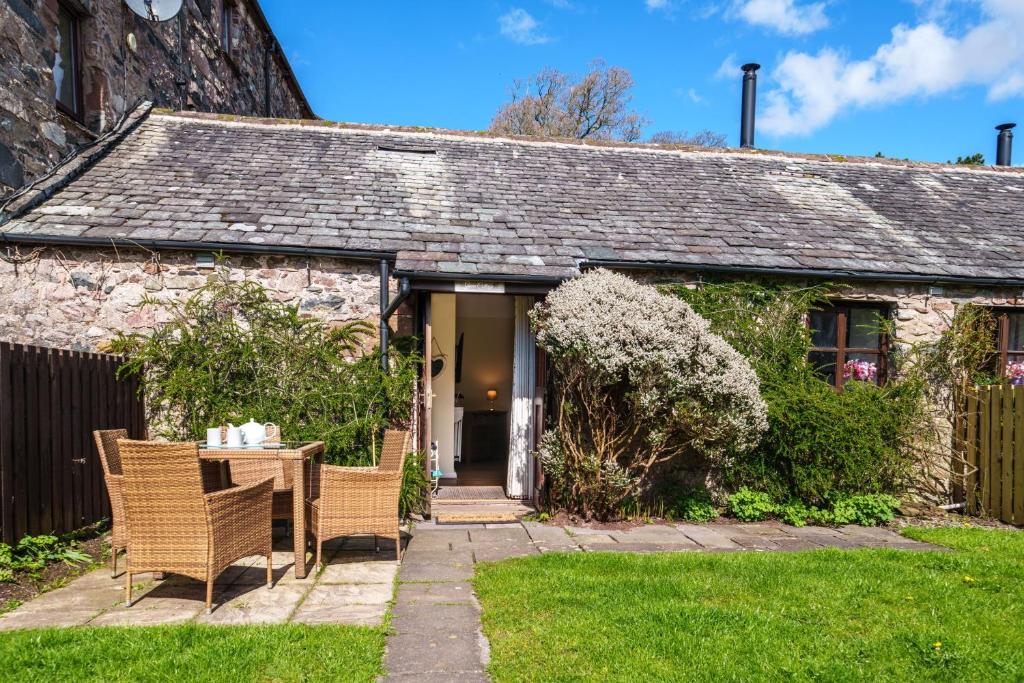 a cottage with a table and chairs in the yard at Gunn Cottage - Dog-friendly enclosed garden in Santon Bridge