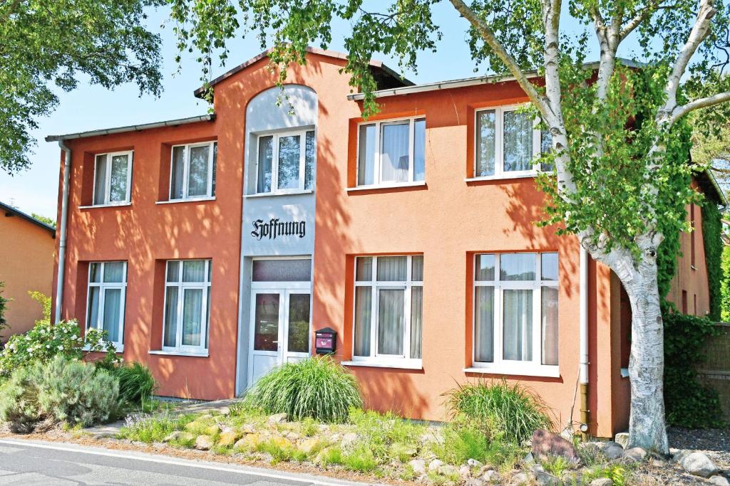 an orange building with a tree in front of it at Appartementhaus auf Moenchgut in Thiessow