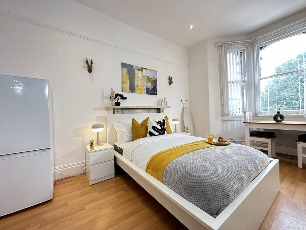 a white bedroom with a bed and a piano at Cozy Studio for Arts & Culture Lovers in Birmingham