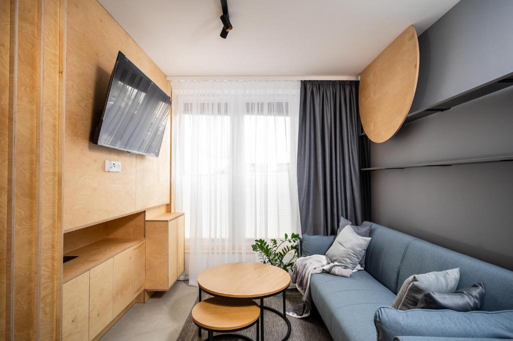 NovaNest Apartments - Kalwaryjska في كراكوف: غرفة معيشة مع أريكة زرقاء وطاولة
