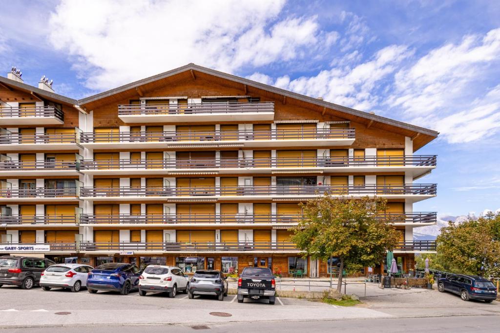 a large building with cars parked in a parking lot at Christiania I F2 - 4 pers - pres des pistes in Nendaz