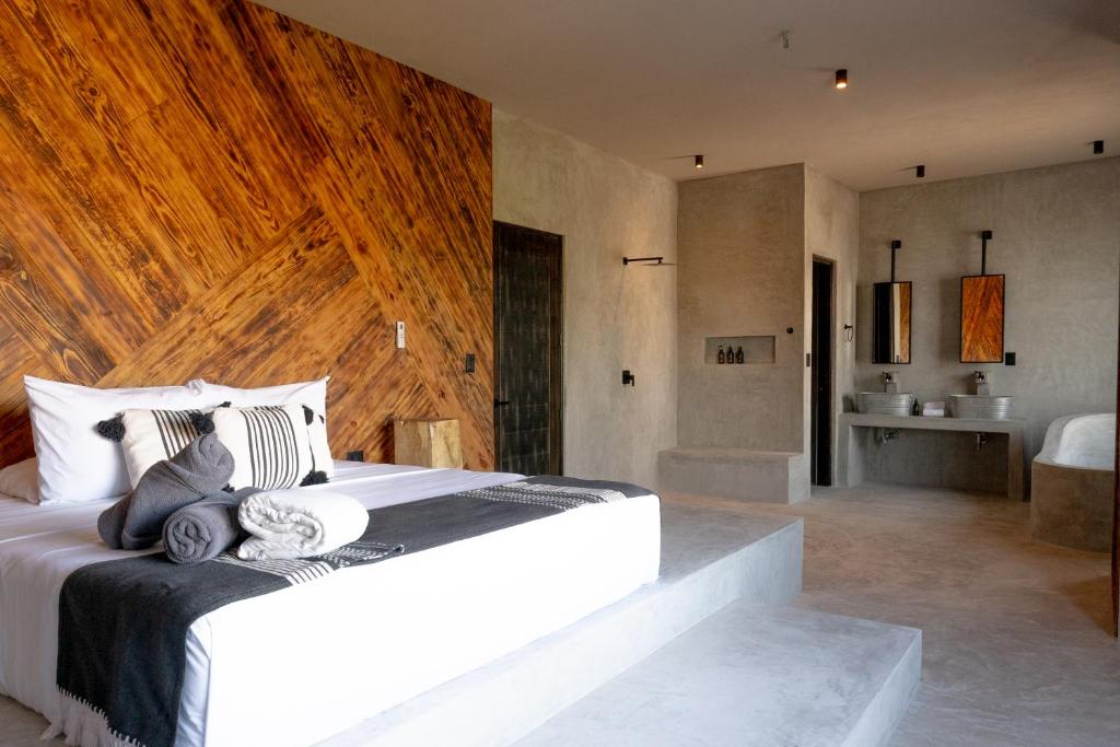 1 dormitorio con 1 cama blanca grande y pared de madera en Macondo Holbox Hotel en Holbox Island