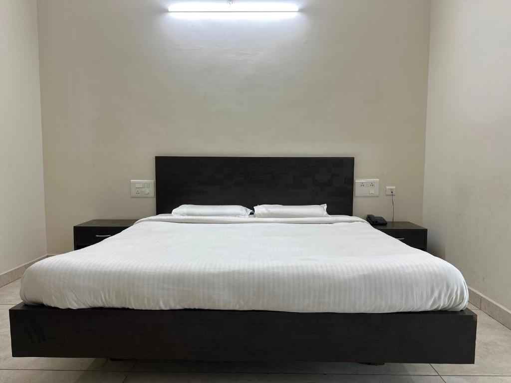 a bedroom with a large bed with white sheets at OYO SAR Residency in Nanjangūd