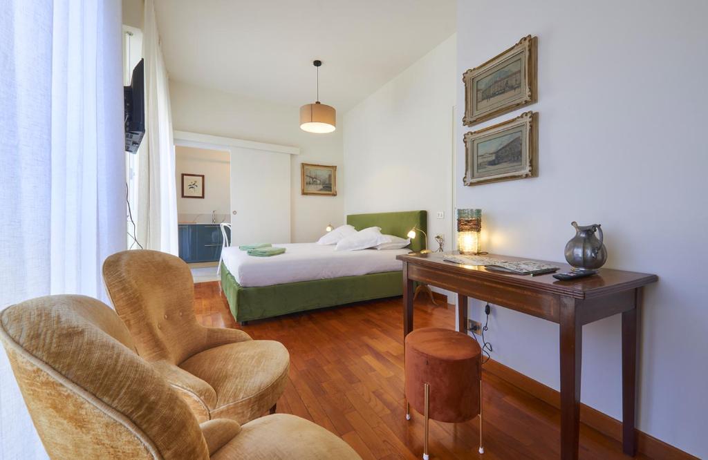 Schlafzimmer mit einem Bett, einem Schreibtisch und Stühlen in der Unterkunft Verde Acqua two Apartments in Lecco