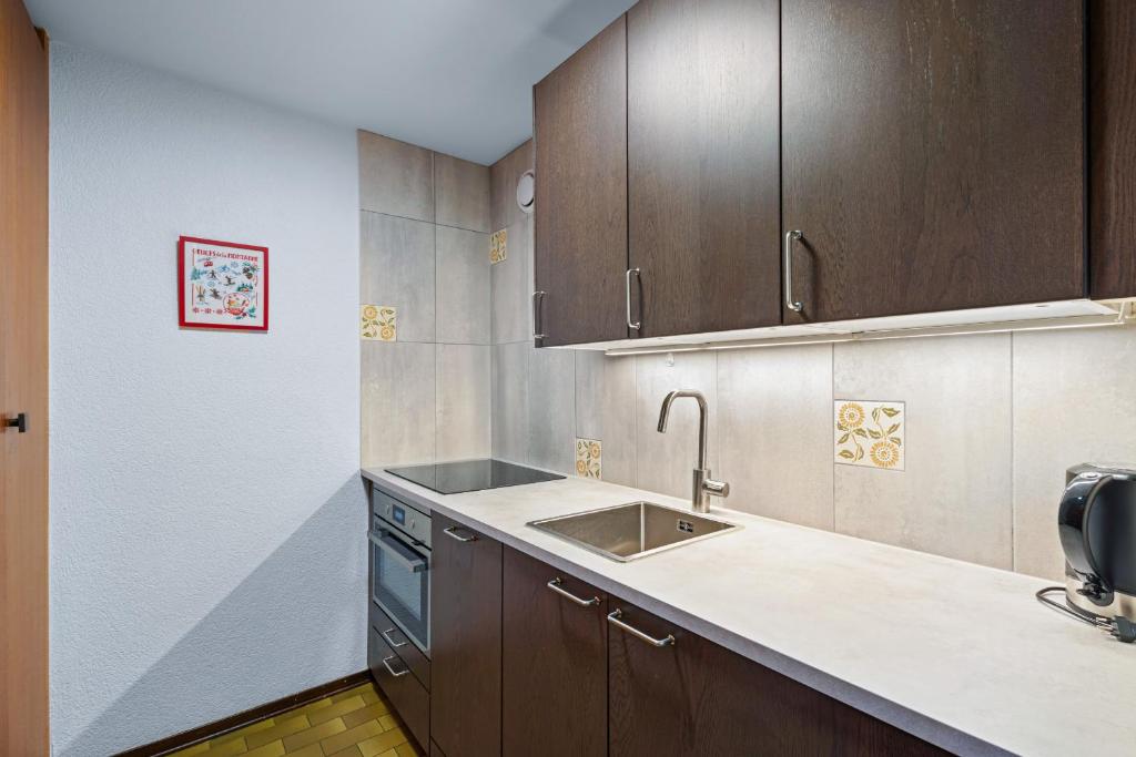 a kitchen with wooden cabinets and a sink at Quille du Diable 46 - 4 pers - piscine in Nendaz