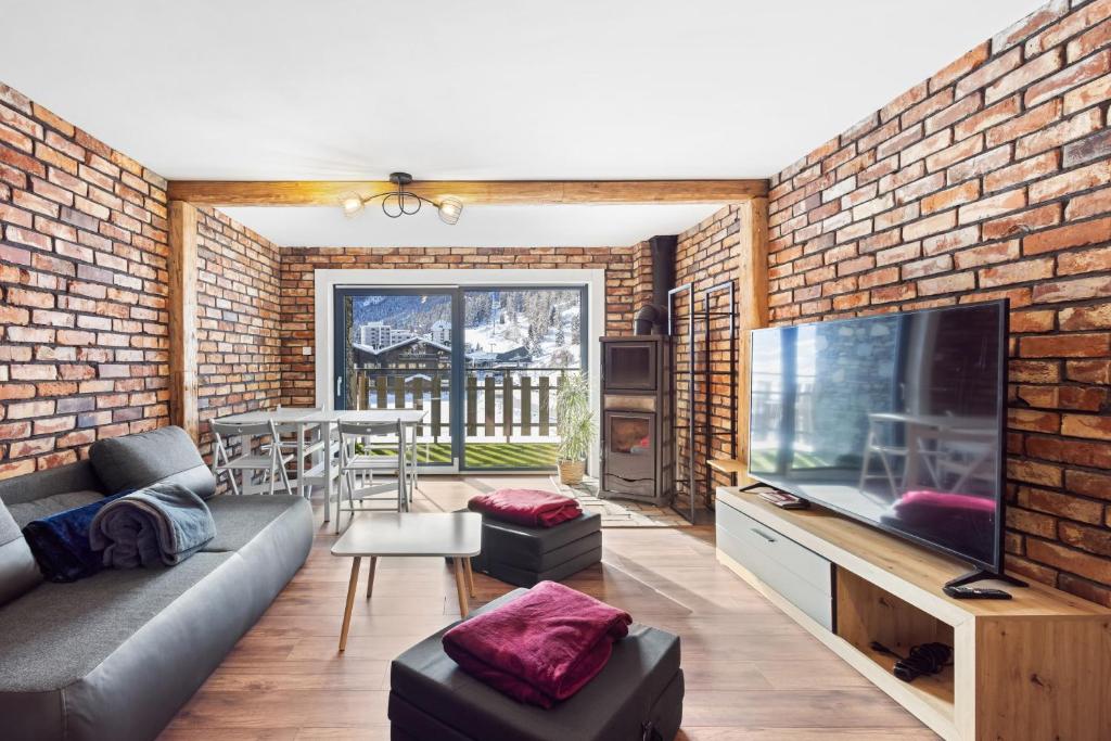 a living room with a brick wall and a large flat screen tv at Dents-Rousses D2 - 4 pers - Siviez in Siviez