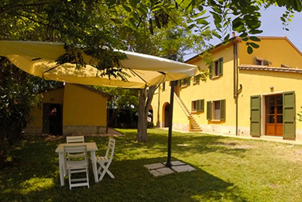 una mesa y sillas bajo una sombrilla frente a una casa en Il Gelso di Francesco - N4, en Cecina