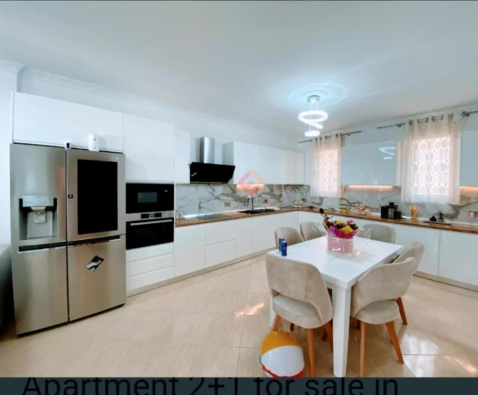 uma cozinha branca com uma mesa e um frigorífico em Seaview em Vlorë