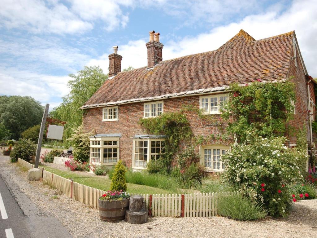 una vecchia casa di mattoni con dei fiori davanti di 4 Bed in Corfe Mullen THOLD a Corfe Mullen