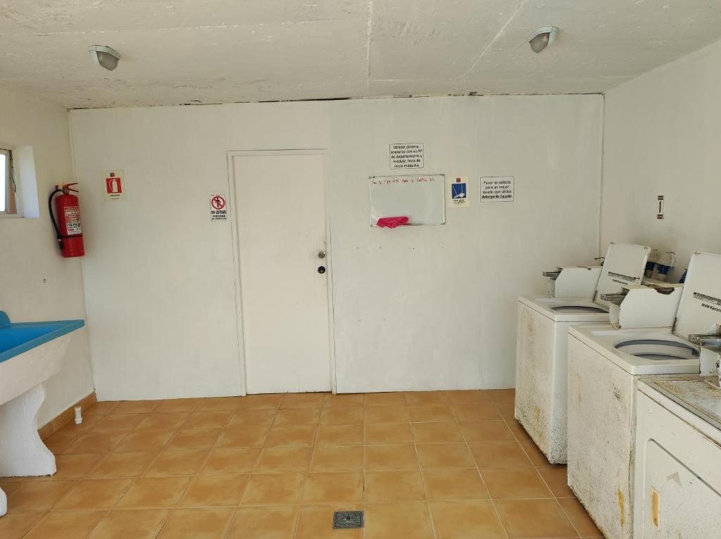 a room with three washing machines and a door at Depto primer piso Quisco Norte in El Quisco