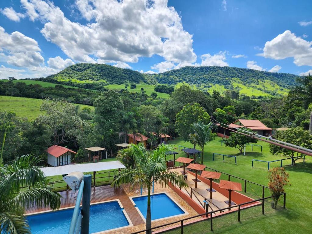 an aerial view of a resort with a swimming pool and mountains at Cabana Hostel nas Árvores EcoPark in São Pedro