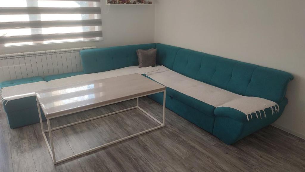 eine blaue Couch mit einem Tisch in einem Zimmer in der Unterkunft Inalux Apartmani Pale in Gornje Pale