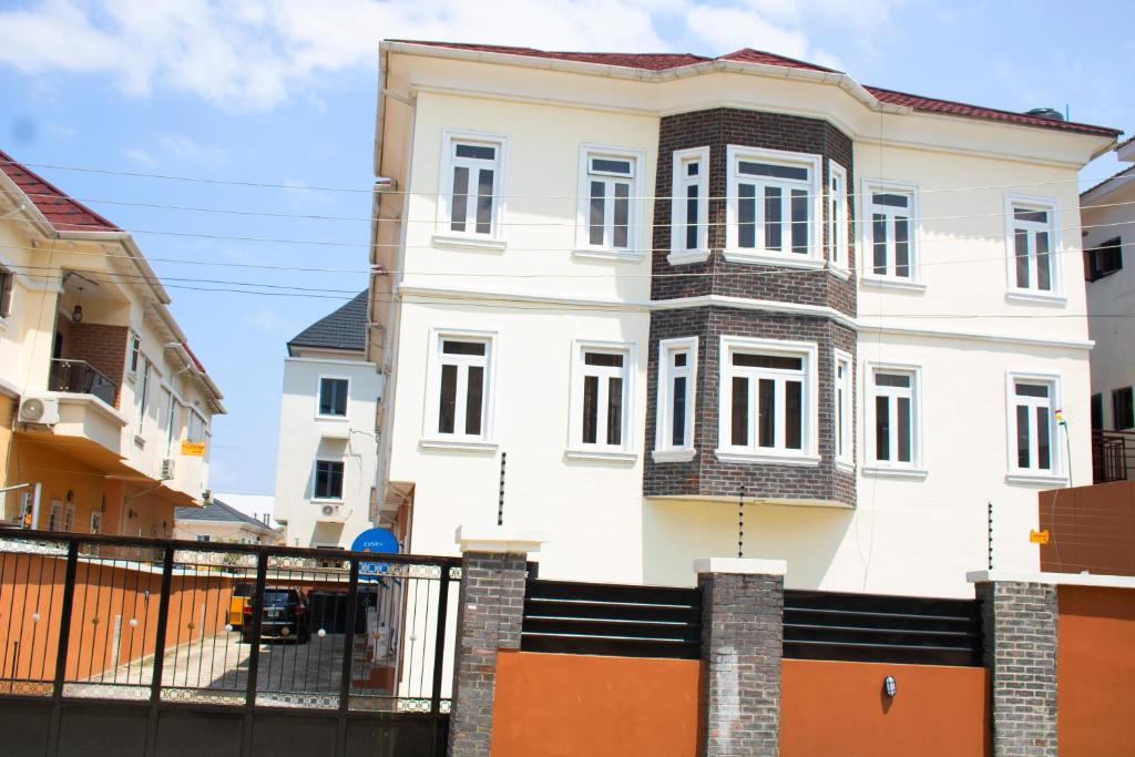 une maison blanche avec une clôture noire devant elle dans l'établissement House 4 Guest House & Apartments, à Lagos