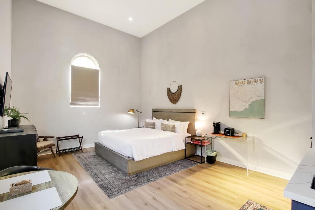 a white bedroom with a bed and a table at Villa Castillo 3 in Santa Barbara