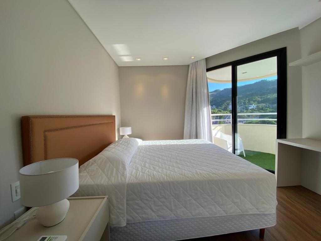 a bedroom with a bed and a large window at Quarto do Praia Brava Hotel in Florianópolis