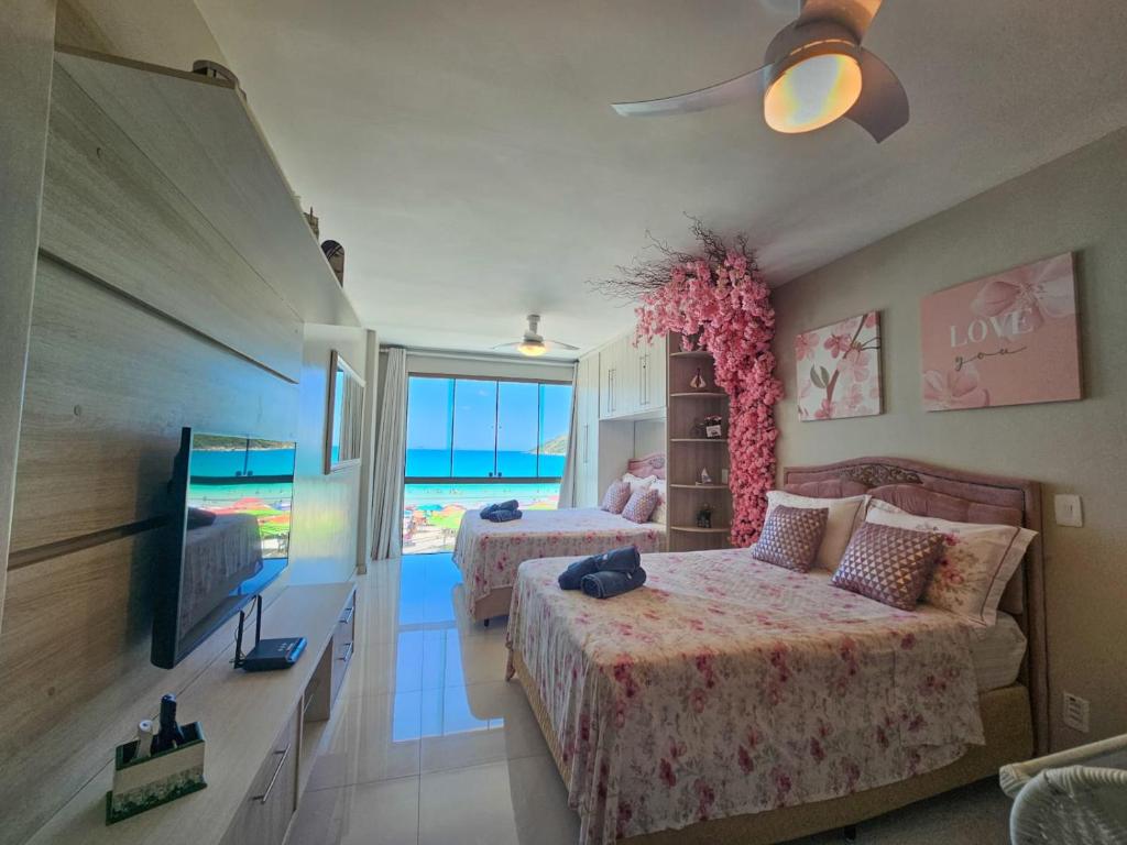 a bedroom with two beds and a flat screen tv at Mar de Cerejeira - Em frente a Prainha in Arraial do Cabo
