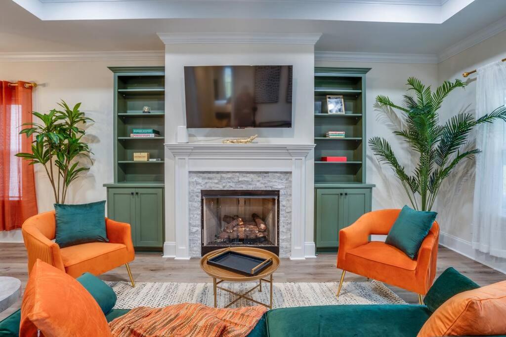 a living room with two orange chairs and a fireplace at Downtown escape: Lakes & Parks - 20min to Airport in Tallahassee