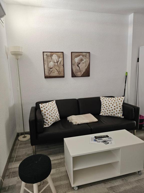 a living room with a black couch and a white table at Apartamentos La Mar in Altea