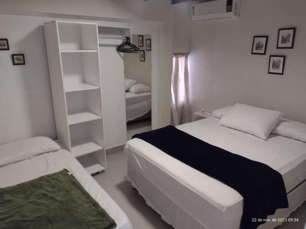 a bedroom with two beds and a book shelf at APARTAMENTO MARISCAL in Bombinhas
