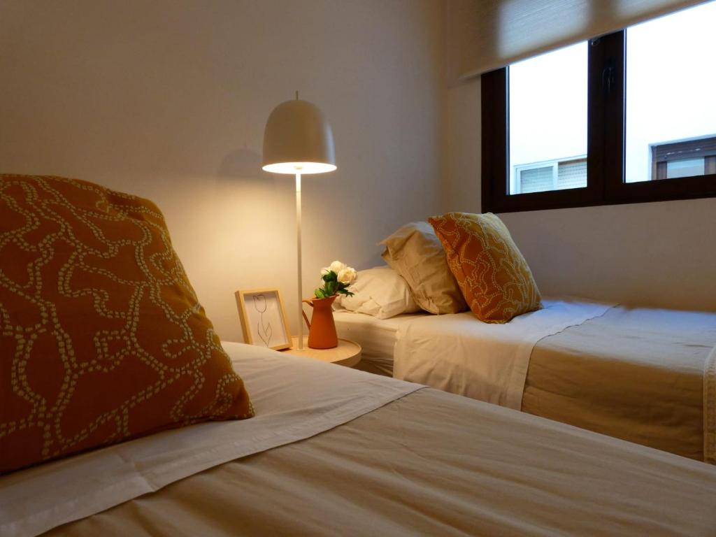 アビラにあるCasa El Paradorのベッド2台と窓が備わるホテルルームです。