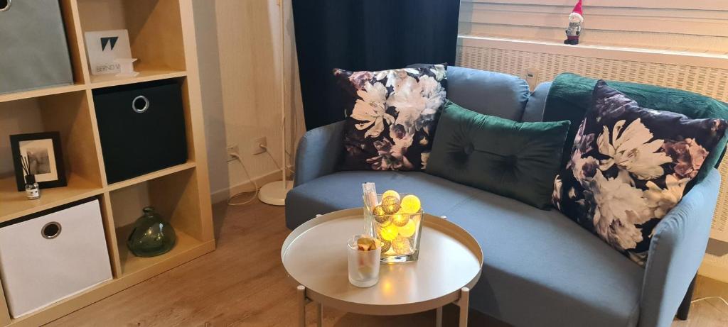ein Wohnzimmer mit einem blauen Sofa und einem Tisch in der Unterkunft Studio KAAN avec terrasse 5mn Basel Airport in Saint-Louis