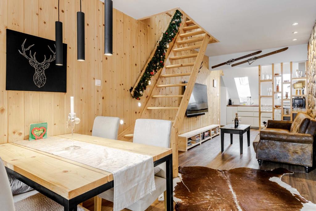 a dining room and living room with a wooden staircase at Apartmán Bruno so saunou in Demanovska Dolina