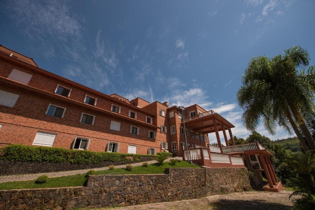 a large brick building with a palm tree in front of it at Farina Park Hotel in Bento Gonçalves